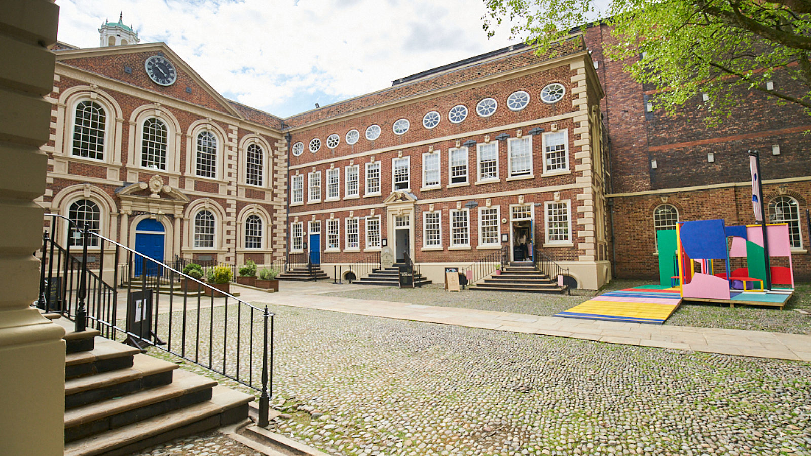 Image shows the Bluecoat building from the courtyard, with Bluecoat Platform, a colourful sculpture, in the right hand corner.