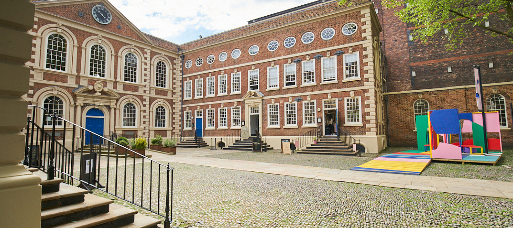 Image shows the Bluecoat building from the courtyard, with Bluecoat Platform, a colourful sculpture, in the right hand corner.