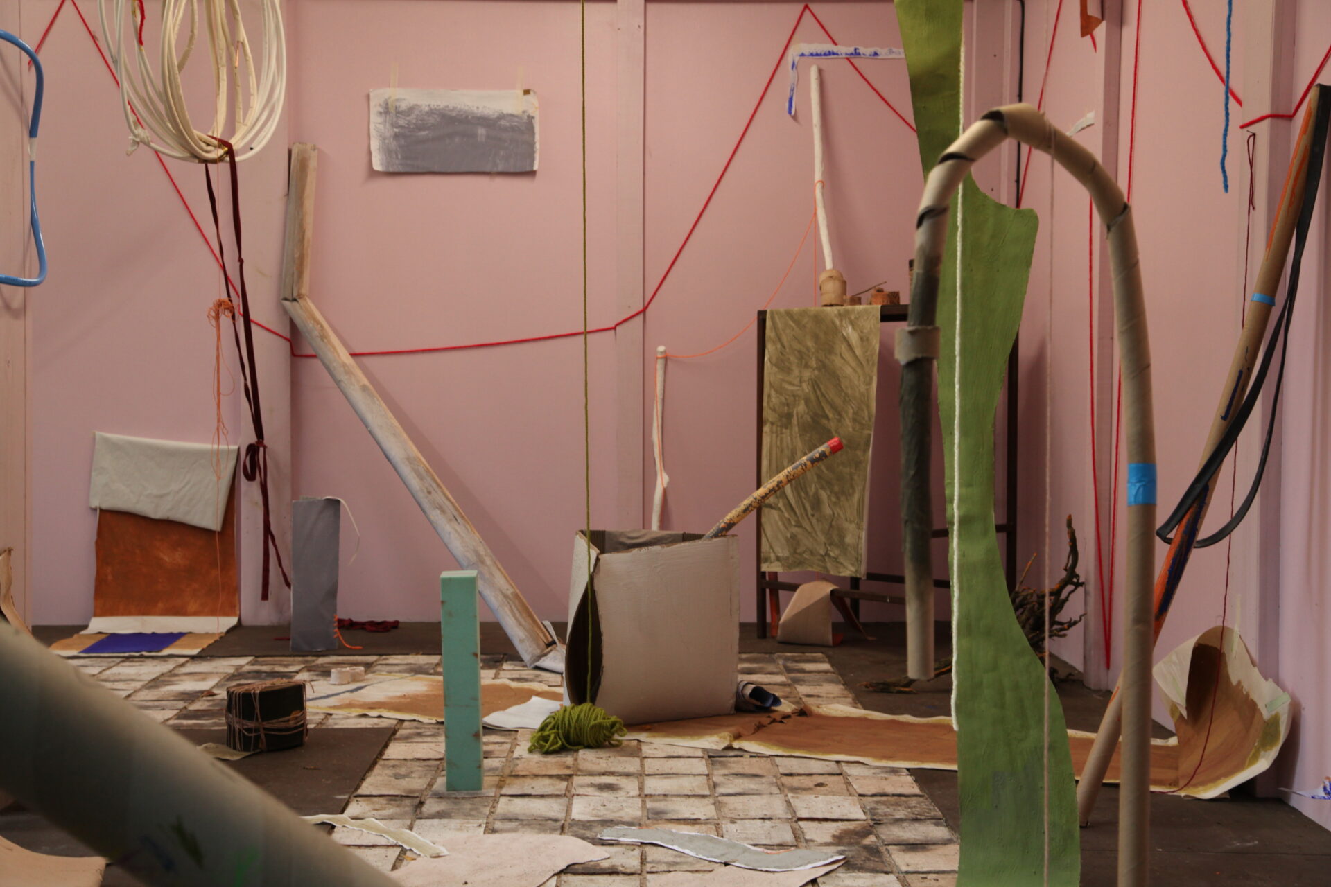 Pink walls are adorned with a variety of different shapes of paper and card in different colours.