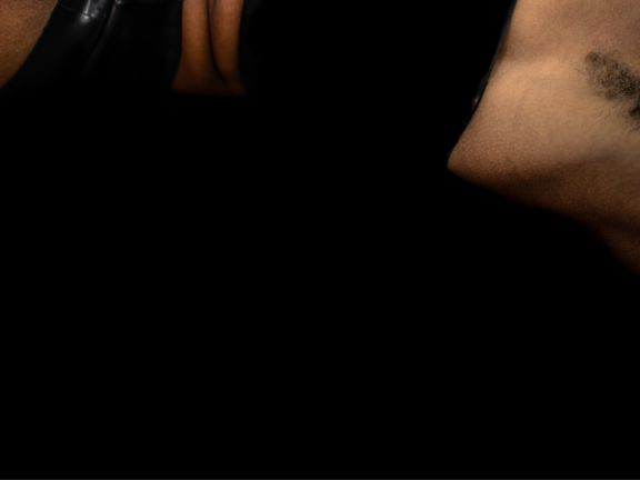 Black background is half covered by the side of a body wearing black underwear with their arm raised.
