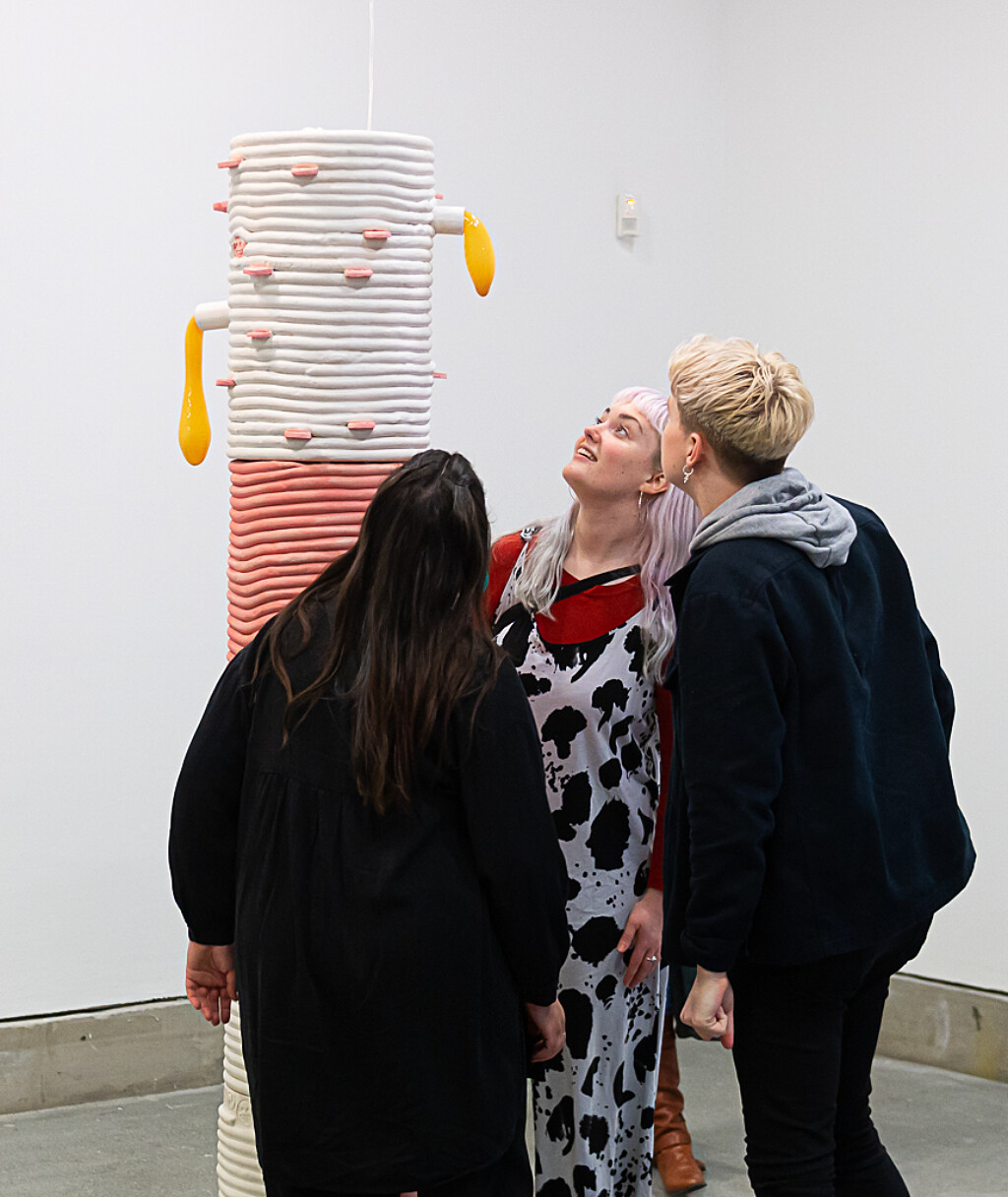 Three people look up towards a large pink and white sculpture by Jonathan Baldock in Bluecoat's Gallery.