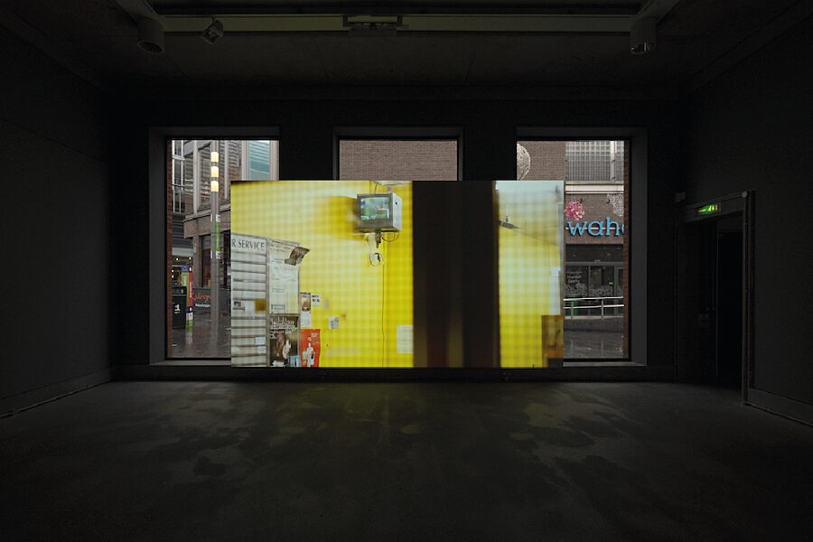 A shot from the film 'Maelfa', showing a room with yellow walls and a small television screen.