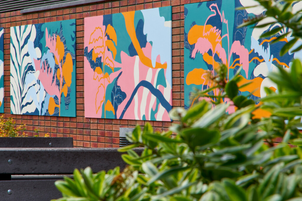A large colourful mural is shown along Bluecoat's external brick wall, with a green bush in the foreground.