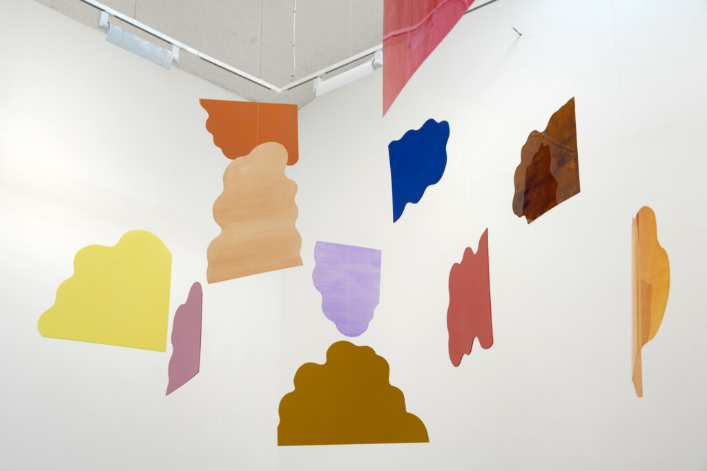 Several colourful shapes suspended in front of a white wall.