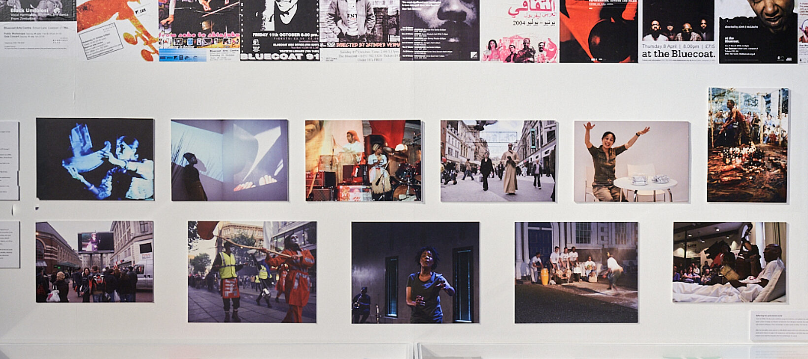 Image shows a variety of posters and photographs on a white wall.