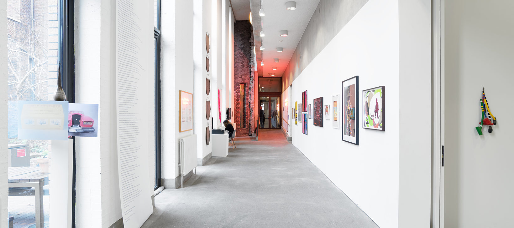 Inside Bluecoat's gallery, there are different artworks along the wall, at the end of the corridor is a red light.