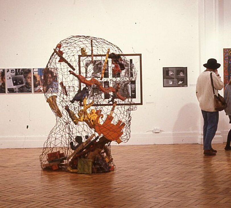 Let The Canvas Come To Life With Dark Faces (1990). Permindar Kaur's Self-portrait stands in the centre, with Rhona Harriette 'As a photographer' series visible behind to the left.
