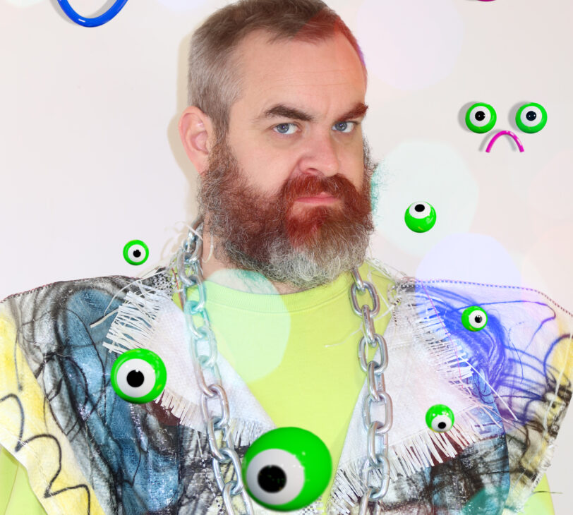 A photograph of the artist Bruce Asbestos, a bearded white man, surrounded by digital drawings of green frogspawn.