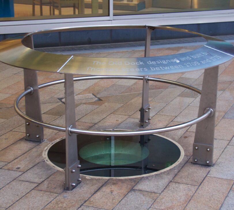 A photo of a glass-covered hole in the ground, surrounded by metal pillars.