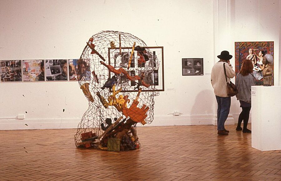 Let The Canvas Come To Life With Dark Faces (1990). Permindar Kaur's Self-portrait stands in the centre, with Rhona Harriette 'As a photographer' series visible behind to the left.